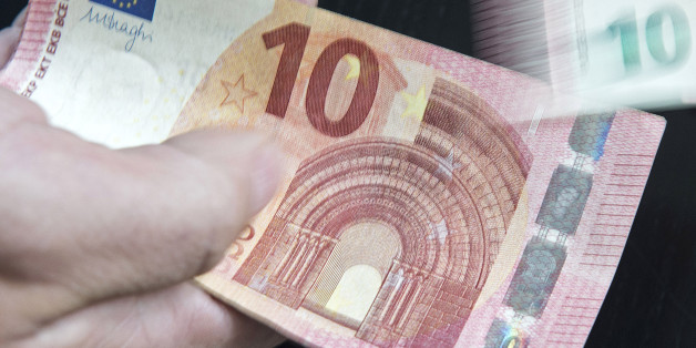 In this picture taken with a long time exposure a counterfeit money expert of the German Federal Bank enumerates new ten euro banknotes during a press conference at the branch office of the German Federal Bank in Erfurt, central Germany, Thursday, Sept. 18, 2014. The new banknote will be introduced in 18 European countries on Sept. 23, 2014. (AP Photo/Jens Meyer)