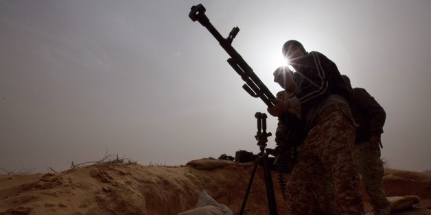 In this Saturday, Feb. 21, 2015 photo, Libyan soldiers try to fix a weapon that jammed during clashes with militants on the frontline in Al Ajaylat, 120 kilometers (75 miles) west of Tripoli, Libya. Army forces in Libya have been fighting Islamic and tribal militias since last September. (AP Photo/Mohamed Ben Khalifa)