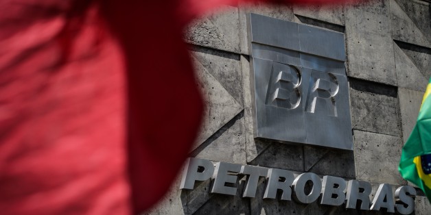 Protesters wave banners outside the headquarters of the Brazilian state-run oil giant Petrobras, during an employees' protest demanding for their job protection in Rio de Janeiro, on March 4, 2015. AFP PHOTO / YASUYOSHI CHIBA (Photo credit should read YASUYOSHI CHIBA/AFP/Getty Images)