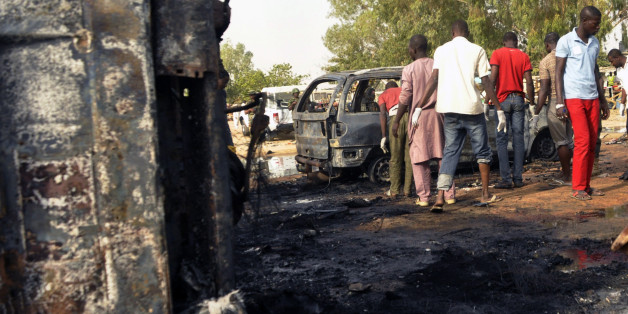 Men inspect the site of a suicide bomb explosion at a bus station in Kano, Nigeria, Tuesday, Feb. 24, 2015. Teenage suicide bombers, suspected to be Boko Haram extremists, killed at least 24 people in separate blasts Tuesday at crowded bus stations in two northern Nigerian cities 300 kilometers (200 miles) apart. (AP Photo/Sani Maikatanga )