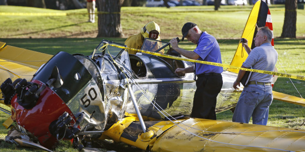 Officials work on the scene of a vintage airplane that crash-landed on the Penmar Golf Course in the Venice area of Los Angeles, Thursday, March 5, 2015. Harrison Ford crash-landed the airplane shortly after taking off from a nearby airport and reporting engine problems. (AP Photo/Damian Dovarganes)