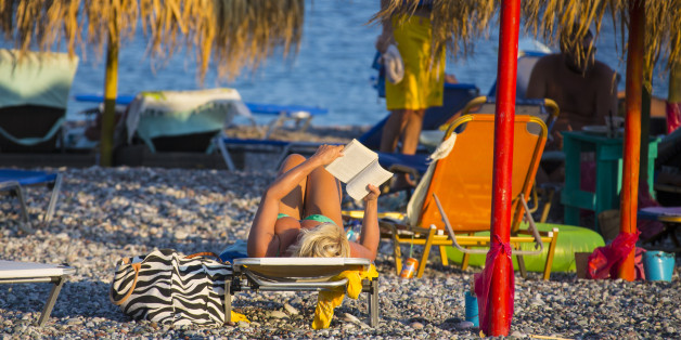 RHODES, GREECE - AUGUST 23: Woman in a bikini is reading and taking a sunbath at the beach in Gennadi on August 23, 2012 in Rhodes, Greece . Rhodes is the largest of the Greek Dodecanes Islands. (Photo by EyesWideOpen/Getty Images)