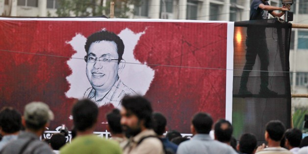 A Bangladeshi activist sets up a light on a poster displaying a portrait of Avijit Roy as others gather during a protest against the Roy in Dhaka, Bangladesh, Friday, Feb. 27, 2015. Roy, a prominent Bangladeshi-American blogger known for speaking out against religious extremism was hacked to death as he walked through Bangladesh's capital with his wife, police said Friday. (AP Photo/A.M. Ahad)