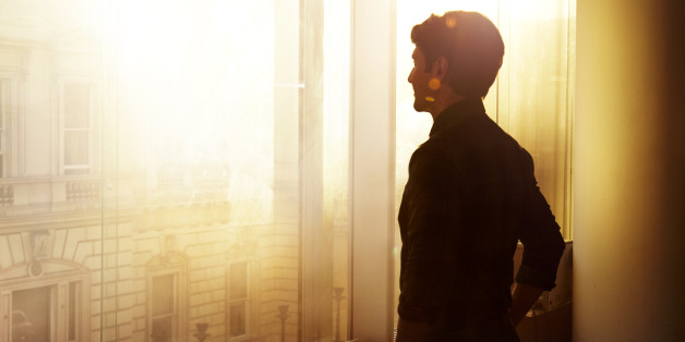 Businessman looking out over the city at sunrise.