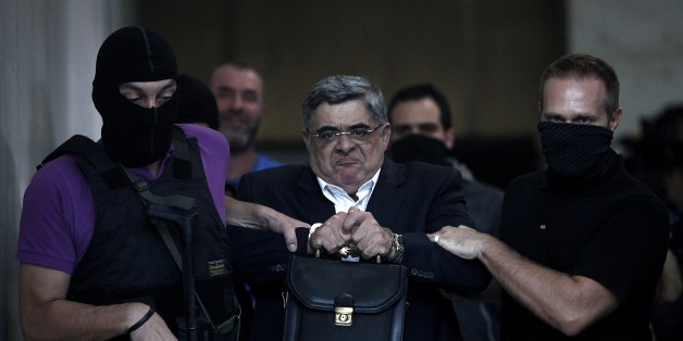 The leader of ultra-right wing Golden Dawn party Nikos Michaloliakos is escorted by masked police officers to the prosecutor from the police headquarters in Athens on September 28, 2013. Greek police on Saturday swooped on the neo-Nazi Golden Dawn party, arresting its leadership and hunting for dozens of members across the country in a crackdown sparked by the murder of a leftist musician. The arrests came a day after Golden Dawn threatened to pull its lawmakers out of parliament, a move that co