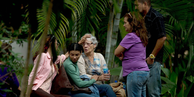 Josefa Alvarez de Gonzalez, center, is comforted by relatives of her husband, Rodolfo Gonzalez, outside the morgue office in Caracas, Venezuela, Friday, March 13, 2015. Rodolfo Gonzalez who was arrested last year during demonstrations against the Venezuela's President Nicolas Maduro government has died in state custody. The family of Gonzalez said that he died while being held at the headquarters of Venezuela's intelligence police. The 64-year-old pilot had been jailed since April 2014 and was