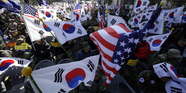 South Korean Vietnam War veterans hold flags from South Korea and the United States during a rally denouncing the attack on U.S. Ambassador to South Korea Mark Lippert in downtown Seoul, South Korea, Monday, March 9, 2015. South Korea's president visited injured U.S. Ambassador Mark Lippert on Monday amid an outpouring of public sympathy and support for the envoy who is recovering from an attack by a knife-wielding man. (AP Photo/Lee Jin-man)