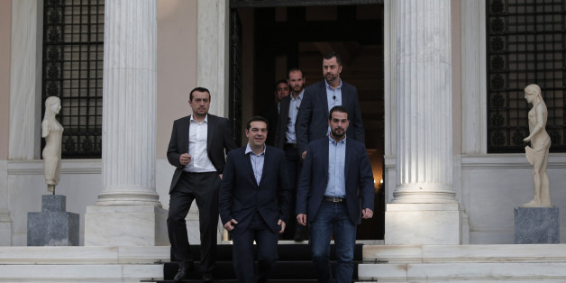 Greece's Prime Minister Alexis Tsipras, center, accompanied by close associates, walks out of his office on his way to the Presidential Palace to attend his government's swearing in ceremony in central Athens, Tuesday, Jan. 27, 2015. Tsipras picked an outspoken bailout critic, Yanis Varoufakis, as his new finance minister Tuesday, signaling his revolve to take a tough line with eurozone lenders in an effort to write off a massive chunk rescue debt. (AP Photo/Lefteris Pitarakis)