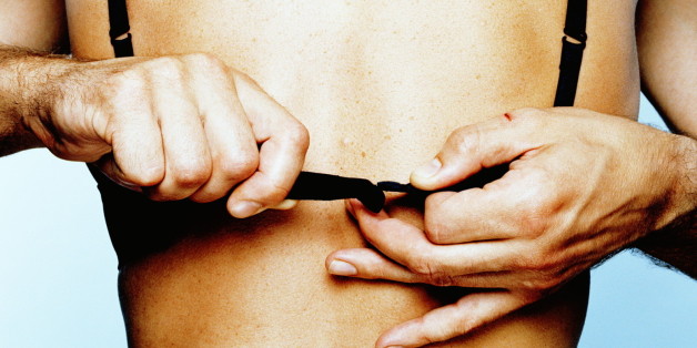 Couple embracing, man unhooking woman's bra, close-up