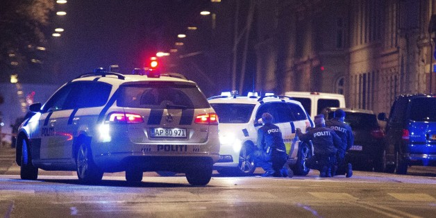Police officers take cover behind their patrol cars on the streets of central Copenhagen on February 15, 2015 after one person was shot in the head and two policemen were shot in the arm and leg in Krystalgade, a street that is home to Copenhagen's main synagogue. It was not confirmed if the incident was related to Saturday's deadly shooting at a cultural centre in Copenhagen where a debate on Islam and free speech was being held. AFP PHOTO / SCANPIX DENMARK / MARTIN SYLVEST +++ DENMARK OUT ++