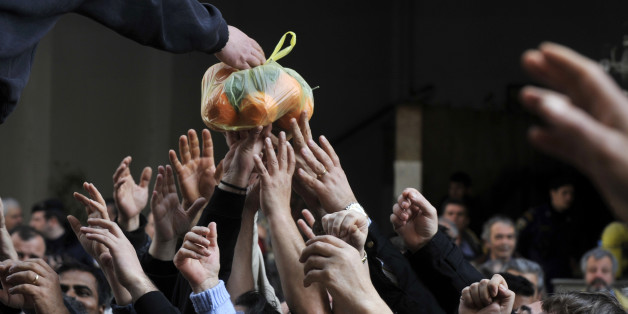 People reach out reach out for a bag of oranges during a free distribution of fruit and vegetables by Greek farmers outside the Agriculture Ministry in Athens part a farmers protest against high production costs, including petrol, on February 6, 2013. Farmers distributed more than 50 tons of fruit and vegetables. AFP PHOTO/ LOUISA GOULIAMAKI (Photo credit should read LOUISA GOULIAMAKI/AFP/Getty Images)