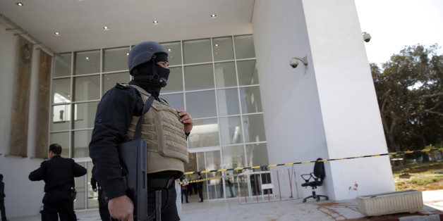 Policemen guard the entrance of the Bardo museum in Tunis, Tunisia, Thursday, March 19, 2015, as a a blood stain is seen at right, a day after gunmen opened fire killing over 20 people, mainly tourists. One of the two gunmen who killed tourists and others at a prominent Tunisian museum was known to intelligence services, Tunisia's prime minister said Thursday. But no formal links to a particular terrorist group have been established in an attack that threatens the country's fledgling democracy and struggling tourism industry. (AP Photo/Christophe Ena)