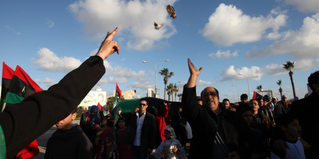 Libyan man throws candies to the people at Tahrir Square, during the second anniversary of the uprising that toppled longtime dictator Moammar Gadhafi in Benghazi, Libya, Sunday, Feb, 17, 2013. (AP Photo/Mohammad Hannon)