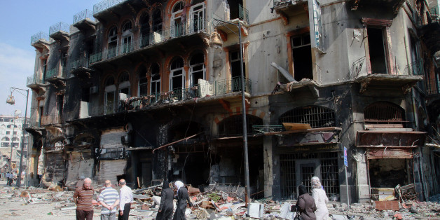 In this photograph made on a military-led media tour, Syrian civilians return to their neighborhood in the old city of Homs, Syria on Friday, May 9, 2014, where bulldozers cleared rubble from the streets of battle-scarred districts in the central Syrian city after government troops entered the last rebel-held neighborhoods as part of an agreement that also granted opposition fighters safe exit from the city. (AP Photo)