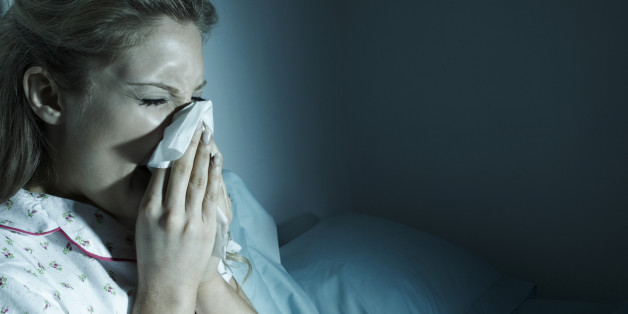 Woman blowing her nose in bed