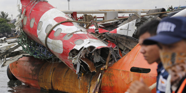 Security guards stand near the newly-recovered remains of the fuselage of the ill-fated AirAsia Flight 8501 on the deck of rescue ship Crest Onyx at Tanjung Priok port in Jakarta, Indonesia, Monday, March 2, 2015. The Airbus A320-200 with 162 people on board crashed into the Java Sea on Dec. 28, 2014 while flying from Surabaya, East Java, to Singapore. (AP Photo/Dita Alangkara)