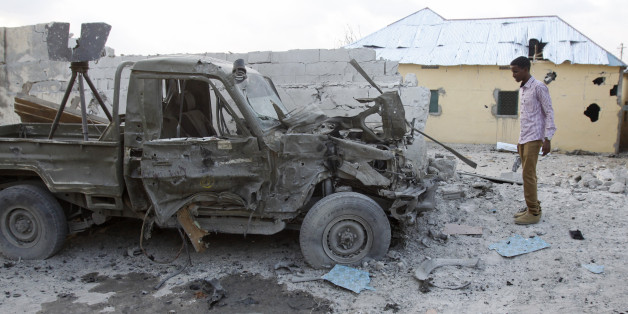 A Somali man stands near the wreckage of a car that carried the bomb and was detonated at the gate of one of Mogadishu's most popular hotels. Friday, March, 27, 2015. A Somali police official says a suicide bomber has detonated his explosives-laden car at the gate of a hotel popular with government officials in Mogadishu. Capt. Mohamed Hussein says gunfire could be heard inside the Maka-Mukarramah Hotel, but it was not clear if any gunmen had managed to penetrate the hotel's gate( AP Photo/Farah Abdi Warsameh)