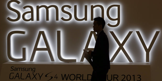 In this photo taken on April 25, 2013, a man walks by a logo of Samsung Electronics Co.'s latest smartphone Galaxy S4 during its unveiling ceremony in Seoul, South Korea. Samsung Electronics Co. has applied for U.S. and South Korean trademarks for a watch that connects to the Internet in the latest sign that consumer technology companies see wearable devices as the future of their business. (AP Photo/Lee Jin-man)
