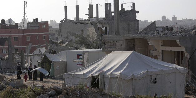 Palestinian women stand in front of a tent they set up next to their destroyed house in the Shijaiyah neighborhood of Gaza City, Monday, March 30, 2015. Despondent over the slow pace of post-war reconstruction, displaced Gazans have begun to return to their damaged homes, patching up the structures with blankets and plastic sheets and living in the unstable and unsafe structures while they wait for promised aid to arrive. (AP Photo/Khalil Hamra)