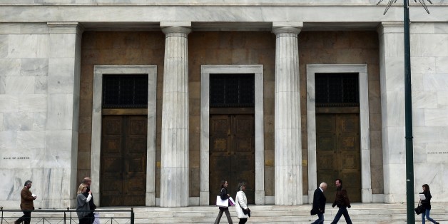 People walk past Bank of Greece headquarters in Athens on March 6, 2015. Greek Prime Minister Alexis Tsipras has requested a meeting with European Commission chief Jean-Claude Juncker, a government source said Friday, after Athens got no help from the European Central Bank to address a cash squeeze. AFP PHOTO/LOUISA GOULIAMAKI (Photo credit should read LOUISA GOULIAMAKI/AFP/Getty Images)