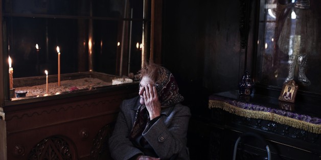A woman sits inside a church during Orthodox Easter celebrations in Athens on April 11, 2015. Millions of Greeks flock to churches around the country this week to celebrate Easter, the country's foremost religious celebration. AFP PHOTO / Angelos Tzortzinis (Photo credit should read ANGELOS TZORTZINIS/AFP/Getty Images)