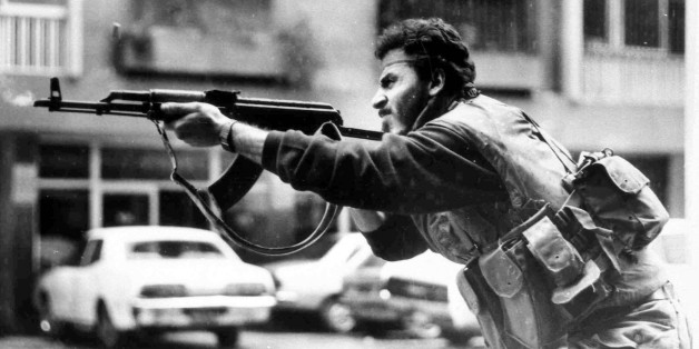FILE - In this Feb. 20, 1987, file photo, a Shiite Muslim AMAL militiaman fires his AK-47 assault rifle during skirmishes with Druse irregulars on Corniche Mazraa road, West Beirut, Lebanon. The Lebanese civil war itself played out in several stages between 1975 and 1990. Over that time, Christians fought Palestinians, Lebanese Sunni and Shiite Muslims and Druse. At one point, Christian groups turned their guns on each other, in a nasty episode of fratricidal bloodshed later repeated by Shiite m