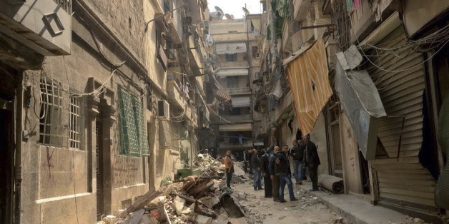 In this photo released by the Syrian official news agency SANA, Syrians gather in a street that was hit by shelling, in the predominantly Christian and Armenian neighborhood of Suleimaniyeh, Aleppo, Syria, Saturday, April 11, 2015. Syrian state television and an activist group say opposition fighters have shelled the government-held neighborhood in the northern city of Aleppo, killing several people and wounding dozens. (AP Photo/SANA)