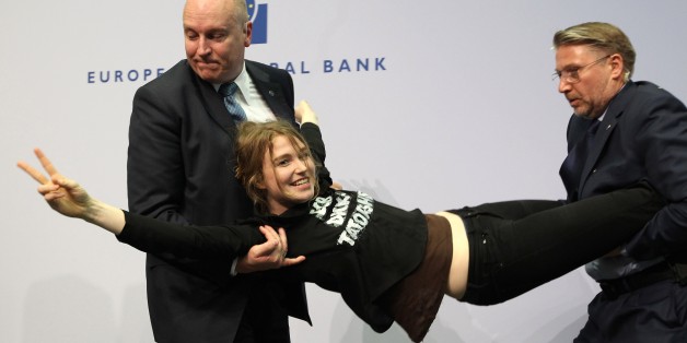 A woman is stopped by security after she interrupted a press conference by Mario Draghi, President of the European Central Bank (ECB) following a meeting of the Governing Council in Frankfurt / Main, Germany, on April 15, 2015. AFP PHOTO / DANIEL ROLAND (Photo credit should read DANIEL ROLAND/AFP/Getty Images)