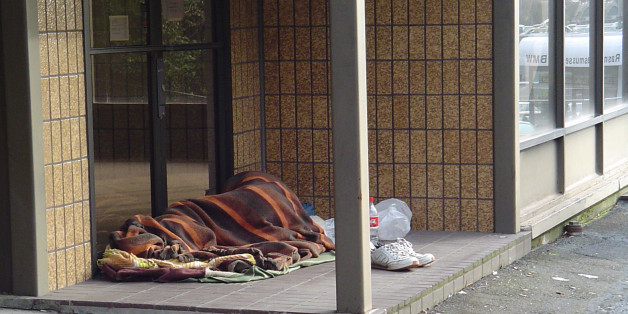 Portland has its share of homeless people. The man (I assume) found a good place to sleep. It is out of the weather and this section of the building is vacant. Note the reflection in the windows to the right. It reads "Rasmussen BMW."
