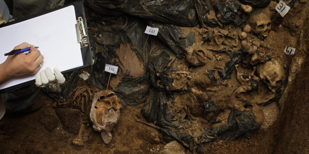 A forensic takes notes at a mass grave found during renovation works at a public school in Mixco, in the outskirts of Guatemala City, Tuesday, Sept. 1, 2009. Investigators say that the skeletons of around 160 corpses found in the grave were moved from the local cemetery because of lack of space. A human rights group that gathers relatives of missing people said that the corpses could be of people who disappeared during Guatemala's internal conflict and asked for an investigations. (AP Photo/Rodrigo Abd)