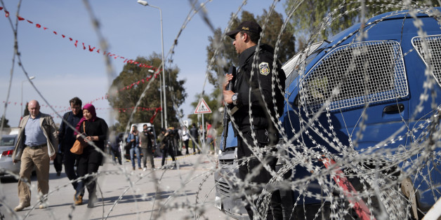 People walk by as as a police officer guards the National Bardo Museum in Tunis, Tunisia, Thursday, March 19, 2015. Tunisian security forces arrested nine people linked to the deadly attack on the National Bardo Museum that left scores dead and wounded and threatened the country's fledgling democracy and struggling tourism industry, the president's office said Thursday. (AP Photo/Christophe Ena)