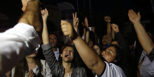 Supporters of the Turkish Cypriots leadership candidate Mustafa Akinci celebrate outside of his campaign office in divided capital Nicosia at the Turkish Cypriot breakaway north part of the divided island of Cyprus, Sunday, April 19, 2015. The election for the Turkish Cypriot leadership will go to a second round after none of the candidates managed to garner enough votes Sunday to avoid a runoff, authorities said, as talks to reunify the ethnically-split island of Cyprus are expected to resume next month. The hard-line incumbent, Dervis Eroglu, and challenger Mustafa Akinci will vie for the leadership of the breakaway north in next week's runoff. Eroglu edged out Akinci by a slight margin, according to an official statement. (AP Photo/Petros Karadjias)