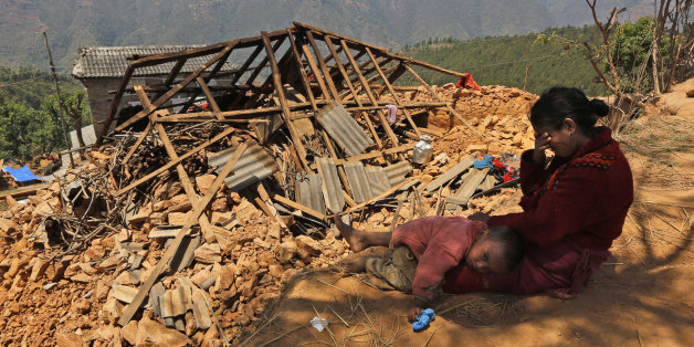 A Nepalese woman sits with her son near their house, destroyed in last week's earthquake, in Pauwathok village, Sindhupalchok district, Nepal, Saturday, May 2, 2015. Life has been slowly returning to normal in Kathmandu, but to the east, angry villagers in parts of the Sindhupalchok district said Saturday they were still waiting for aid to reach them. In the village of Pauwathok, where all but a handful of the 85 houses were destroyed, three trucks apparently carrying aid supplies roared by with