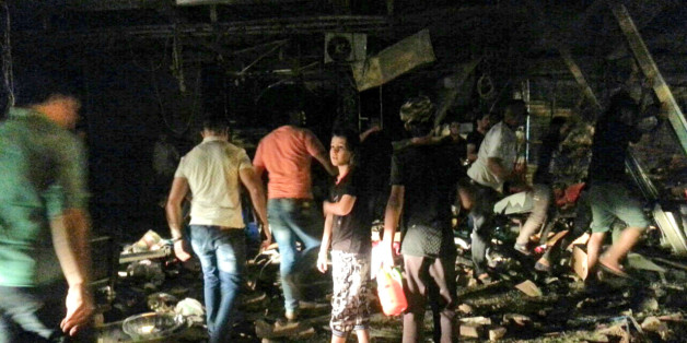 Civilians inspect the site of a bomb attack near restaurants and coffee shops filled with customers in central Baghdad's busy commercial Karradah neighborhood, Iraq, Saturday, May 2, 2015. Police say two bombs, one a suicide car bomb and the other a car bomb, went off just 10 minutes apart in the heart of Baghdad, left many civilians killed and others wounded, officials said. (AP Photo/Hadi Mizban)