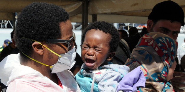 A woman tends to a crying child as migrants disembark from the Italian Navy frigate Bersagliere at the Reggio Calabria harbor, Italy, Monday, May 4, 2015. Italy's Coast Guard and Navy as well as tugs and other commercial vessels joined forces to rescue migrants in at least 16 boats Sunday, saving hundreds of them and recovering 10 bodies off Libya's coast, as smugglers took advantage of calm seas to send packed vessels across the Mediterranean. Sunday's drama at sea came a day after 3,690 migran