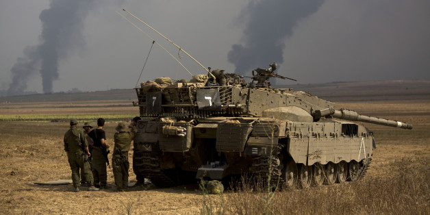 Israeli soldiers stand behind a tank as heavy smoke rises from the Gaza Strip Tuesday, July 22, 2014. Israeli airstrikes pummeled a wide range of targets in the Gaza Strip on Tuesday as the U.N. chief and the U.S. secretary of state began an intensive effort to end more than two weeks of fighting that has killed hundreds of Palestinians and tens of Israelis. (AP Photo/Dusan Vranic)