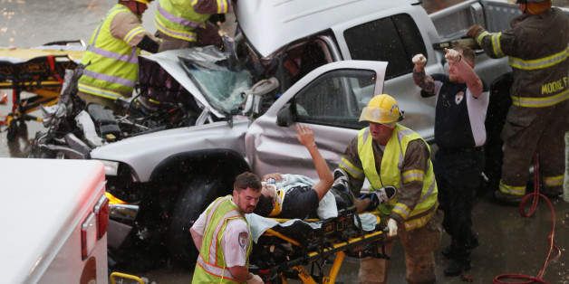 The driver of a truck which crashed during severe weather on Interstate 35 gestures to his rescuers after being cut from the truck in Moore, Okla., Wednesday, May 6, 2015. Forecasters declared a tornado emergency for Moore. (AP Photo/Sue Ogrocki)