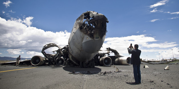 An airport official uses his mobile to take pictures of the wreckage of a military transport aircraft destroyed by Saudi-led airstrikes, at the Sanaa International airport, in Yemen, Tuesday, May 5, 2015. A Saudi-led coalition continues to bomb Shiite rebels also known as Houthis and allied forces across the country. The airstrikes campaign, which began on March 26, and the ground fighting have killed hundreds and displaced at least 300,000 Yemenis. (AP Photo/Hani Mohammed)