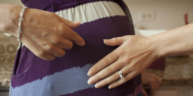 Emily Jordan, right, examines the pregnant belly of her mother Cindy Reutzel on Sunday, Aug. 19, 2012 in Naperville, Ill. After Jordan underwent a radical hysterectomy, she and her husband took up an offer from Reutzel to act as their surrogate. (AP Photo/Sitthixay Ditthavong)