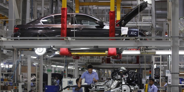 India's retired cricket star Sachin Tendulkar, center, fixes a gear shift to an engine as he assembles a BMW 5 Series at BMW's manufacturing facility on the outskirts of Chennai, India.