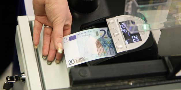 A cashier inspects a euro banknote in a supermarket in Vilnius on January 1, 2015. Lithuania switched over to the euro on Thursday, becoming the last Baltic nation to adopt Europe's single currency in a bid to boost stability despite fears of inflation and eurozone debt woes. AFP PHOTO / PETRAS MALUKAS (Photo credit should read PETRAS MALUKAS/AFP/Getty Images)