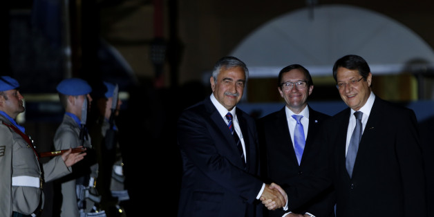 Cyprus' president Nicos Anastasiades, right, and Turkish Cypriot leader Mustafa Akinci shake hands as the United Nations envoy Espen Barth Eide, center, smiles before a dinner at the Ledra Palace Hotel inside the UN controlled buffer zone that divides the Cypriot capital Nicosia, on Monday, May 11, 2015. The dinner is the first meeting between Anastasiades and Akinci since the Turkish Cypriot politician _ a left-wing moderate _ soundly defeated the hard-line incumbent in an election last month.