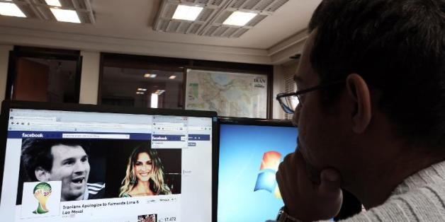 Un Iranien regarde une page Facebook contenant des informations concernant la star du football argentin Lionel Messi (g) et le mannequin brésilien Fernanda Lima, à son bureau à Téhéran, le 9 décembre 2013