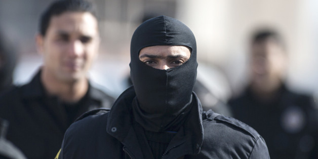A hooded member of the Tunisian anti-terrorist police forces (BAT) walks near a house where suspected Islamist militants were hidden in Raoued, near Tunis, Tuesday, Feb. 4, 2014. Tunisia's police exchanged gunfire with a group of suspected Islamic militants holed up in a house in a suburb near the capital on Tuesday, leaving two militants and a policeman dead, an Interior Ministry spokesman said Tuesday. (AP Photo/Aimen Zine)