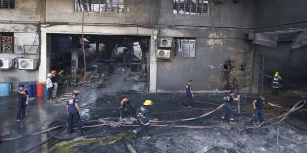Firemen work to put the fire under control at a still-smoldering Kentex rubber slipper factory in Valenzuela city, a northern suburb of Manila, Philippines, Wednesday, May 13, 2015. A fire gutted the factory, possibly killing dozens of workers who ran to the second floor in hopes of escaping only to become trapped by inferno, officials said. Fire officials said there were no survivors found after the fire was put under control, said Mayor Rex Gatchalian of Valenzuela. (AP Photo/Bullit Marquez)