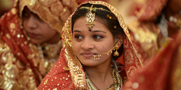 An Indian Muslim bride gestures during a mass wedding ceremony at the ancient Sarkhej Roja in Ahmedabad on February 22, 2013. Some 151 couples participated in a mass marriage organised by Hussaini Waqaf Committee. Participation in mass marriages in the Muslim and Hindu communities are on the rise against the 'Dowry System' in which huge donations are paid by the bride's family members to the family members of the grooms. Instead, in the mass marriages the brides are gifted with the basic necesi