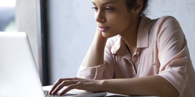 Close up portrait of a young black woman looking at laptop