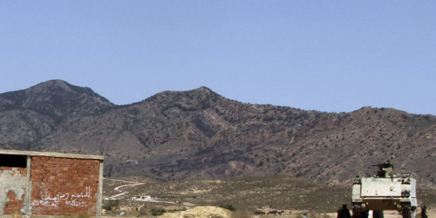 FILE - In this June 25, 2013 file photo, a Tunisian armored personnel carrier patrols near the Jebel Chaambi mountain. Writing on building at left reads: "For Sale". Militants in eastern Tunisia staged two simultaneous attacks on army posts while soldiers held a Ramadan feast, killing at least 14 soldiers, authorities said Thursday July 17, 2014. An extremist group believed linked to al-Qaida's North Africa arm claimed responsibility for the attacks on Mount Chaambi on its Facebook page, calling Tunisian security forces "tyrants".(AP Photo/Paul Schemm, File)