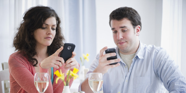 USA, New Jersey, Jersey City, Couple having dinner and text messaging