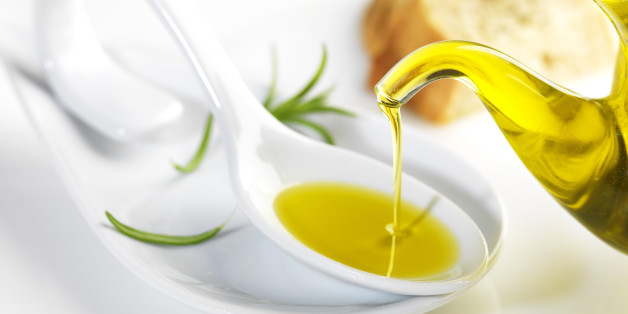 bottle pouring virgin olive oil in a porcelain spoon